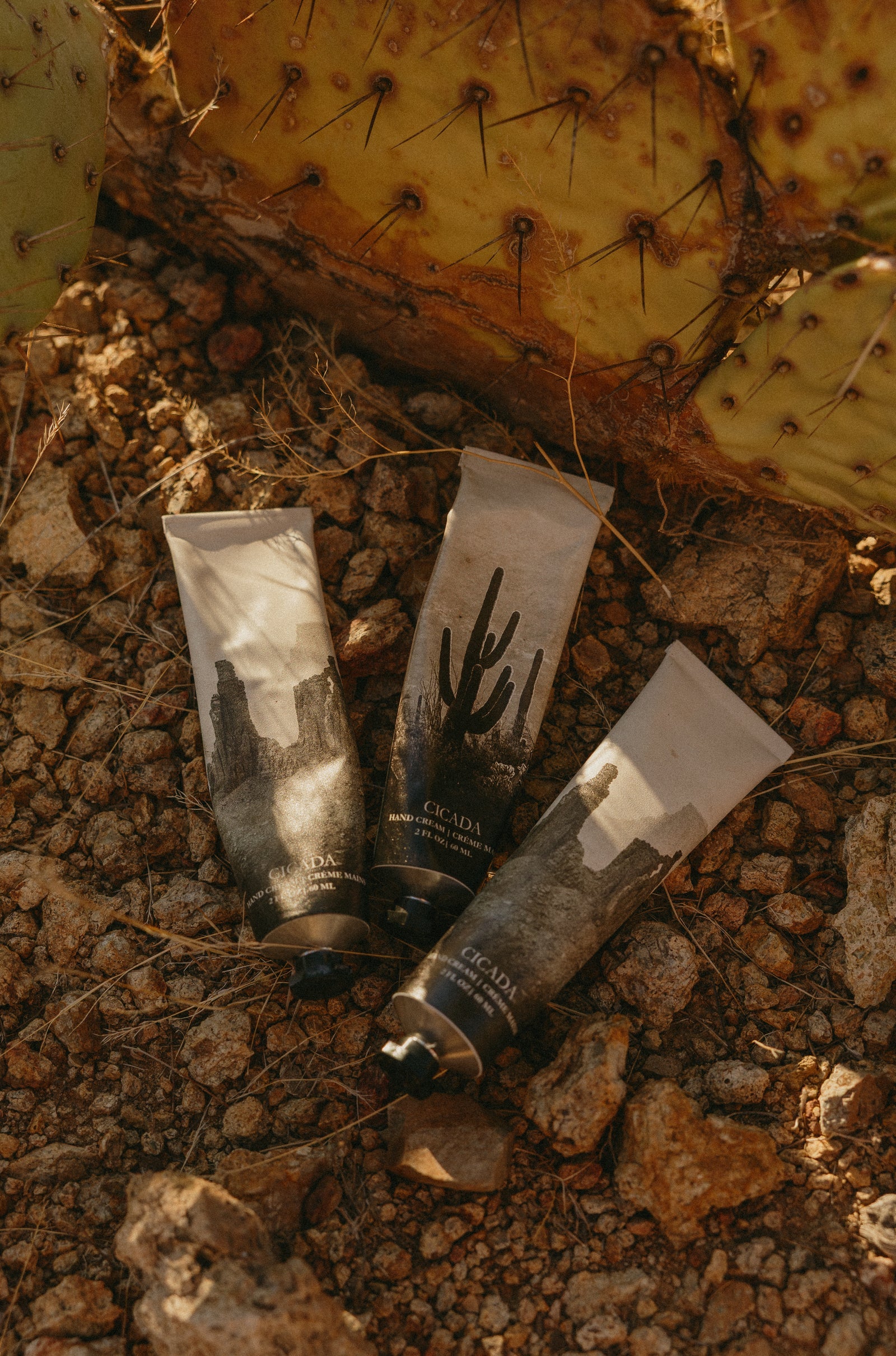 Three tubes of cream or lotion on a textured, natural surface.